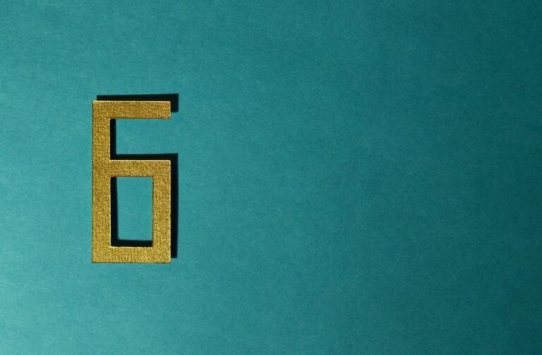 Chiffre 6 doré sur fond bleu-vert texturé, symbole de numérologie