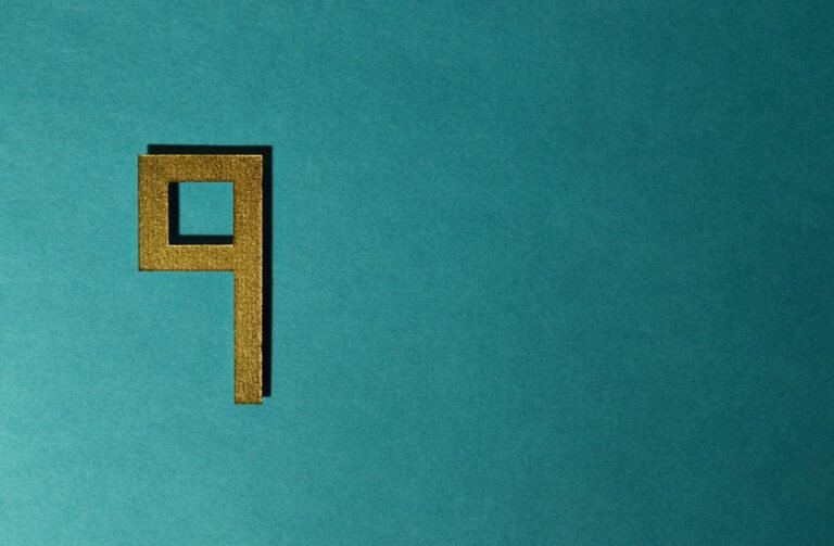 Chiffre 9 doré posé sur un fond texturé bleu-vert, symbole de la numérologie