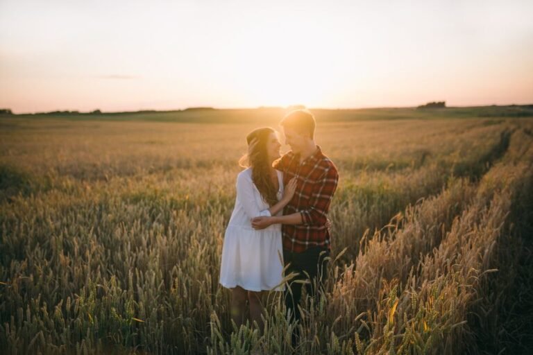 Couple enlacé dans un champ au coucher de soleil