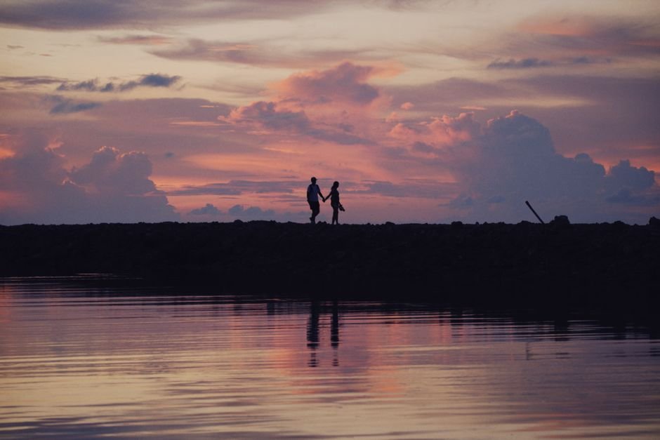 Couple main dans la main en silhouette au coucher du soleil