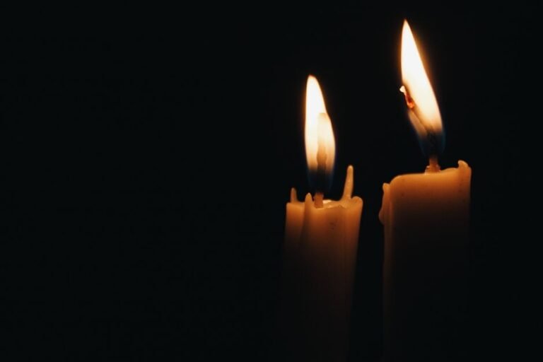 Deux bougies allumées côte à côte dans l'obscurité, symbole des flammes jumelles